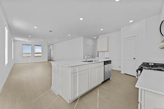 a large white kitchen with a sink a stove and a refrigerator