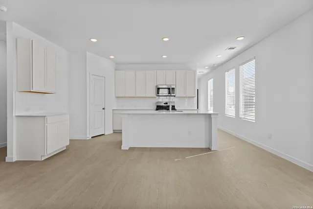 a view of kitchen with kitchen island white cabinets and stainless steel appliances