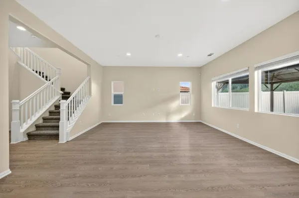 a view of an empty room with wooden floor and stairs