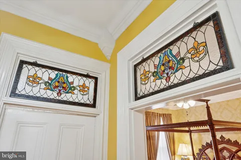 a bedroom with a bed wooden floor and a large window