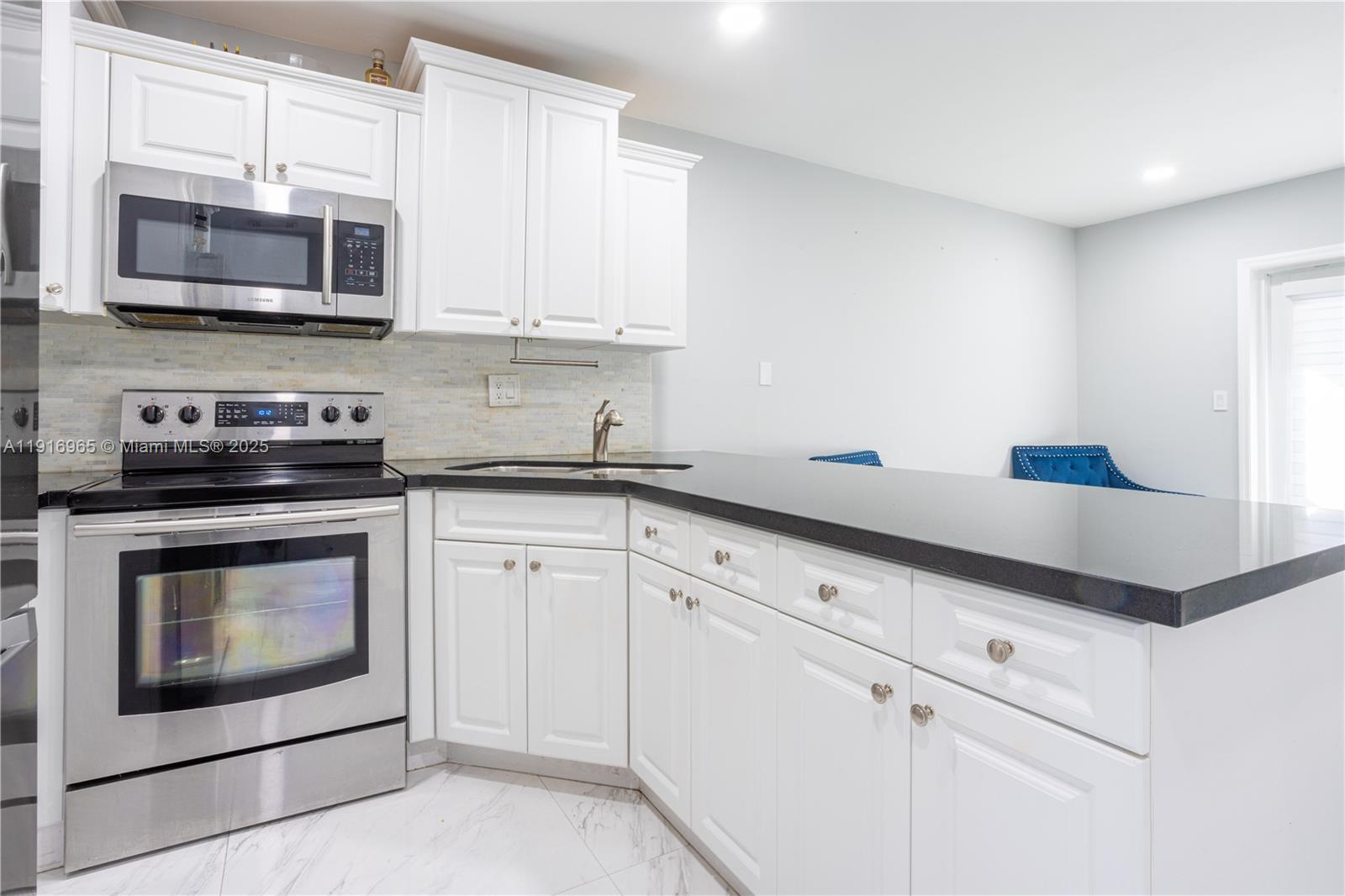 11510 Southwest 7th Street Sweetwater, FL 33174 - Photo 5 of 17 a kitchen with stainless steel appliances granite countertop white cabinets a stove top oven a sink and dishwasher