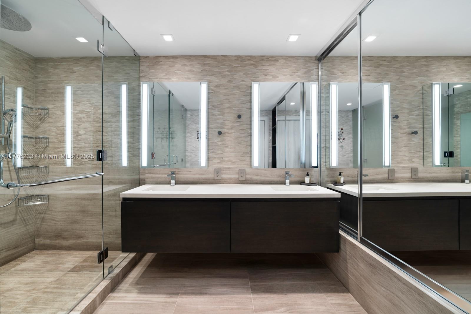 1 Collins Avenue, Unit 401 Miami Beach, FL 33139 - Photo 17 of 25 a bathroom with a double vanity sink large mirror and a bathtub