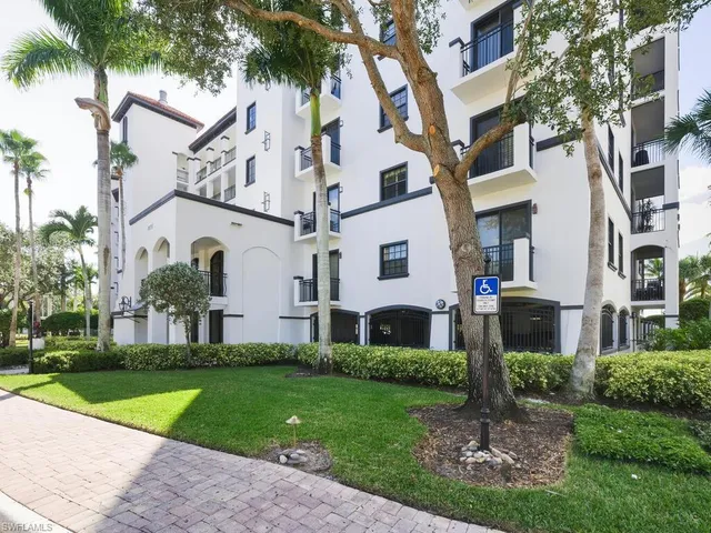 a front view of a white house with a yard and palm trees
