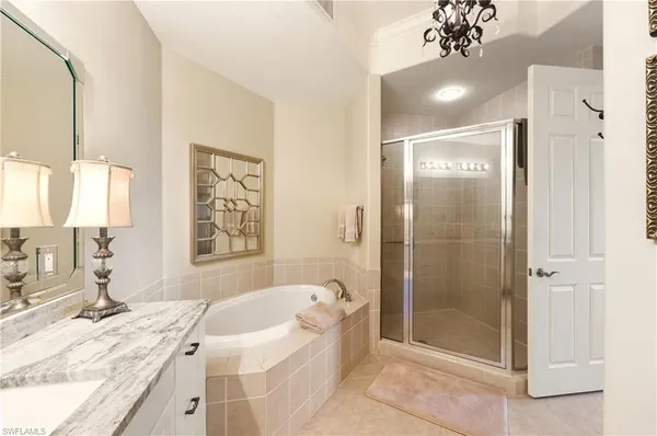 a bathroom with a granite countertop sink a mirror a bathtub and shower
