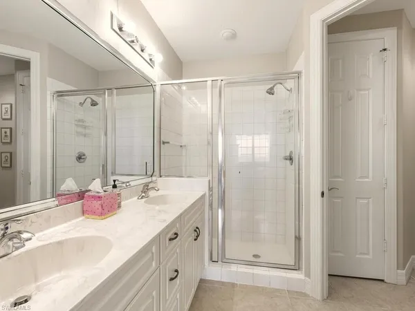 a bathroom with a double vanity sink mirror and shower