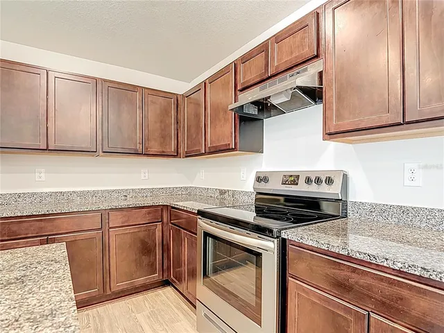 a kitchen with granite countertop a stove sink and cabinets