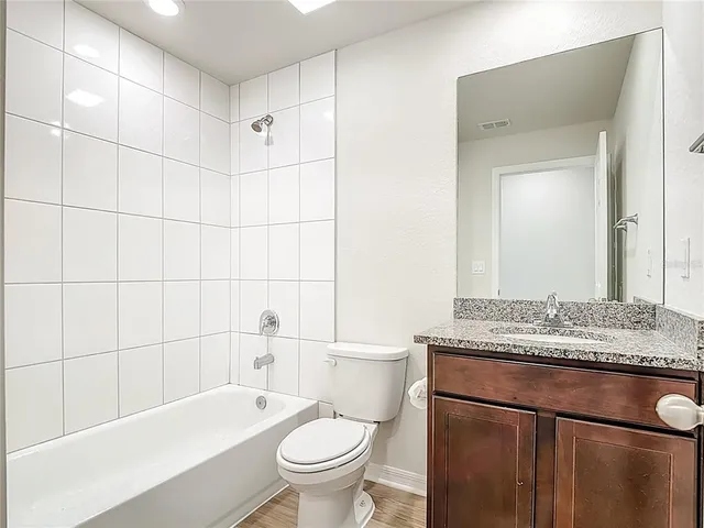 a bathroom with a granite countertop sink toilet mirror and bathtub