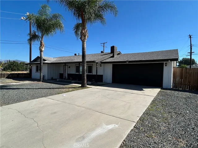 front view of a house with a yard and palm trees