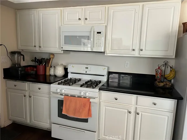 a kitchen with white cabinets and white appliances