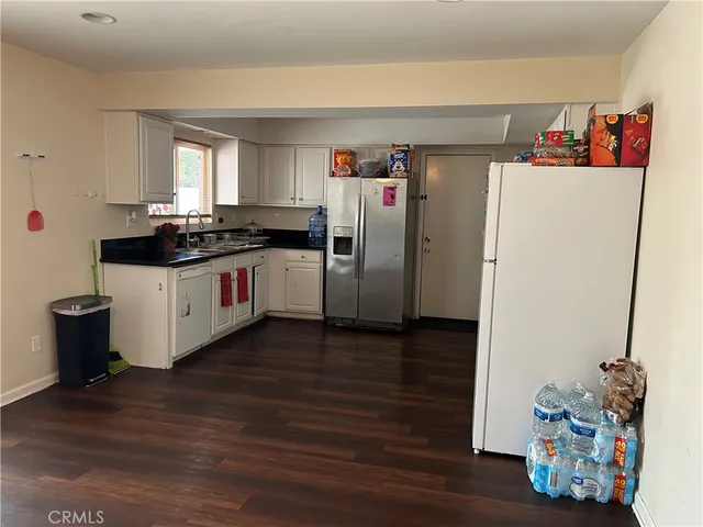 a kitchen with refrigerator and wooden floor