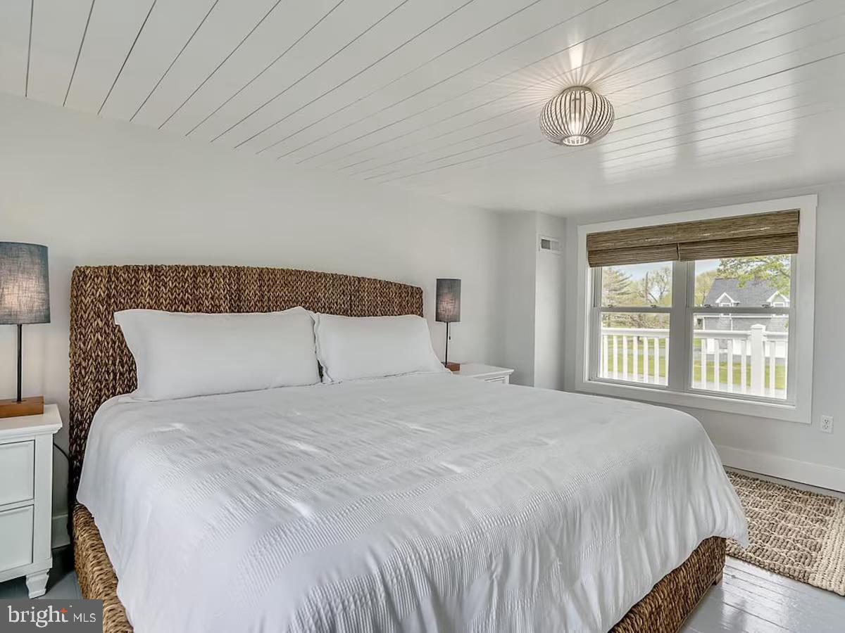 21642 Chicken Point Road Tilghman, MD 21671 - Photo 43 of 63 a large bed sitting in a bedroom next to a window and a chandelier