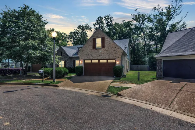a front view of a house with a yard and trees