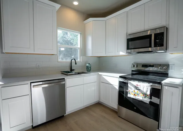 a kitchen with stainless steel appliances granite countertop a sink a stove a microwave and wooden cabinets