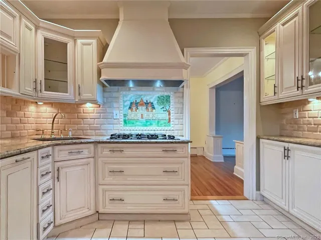 a kitchen with granite countertop a stove and white cabinets