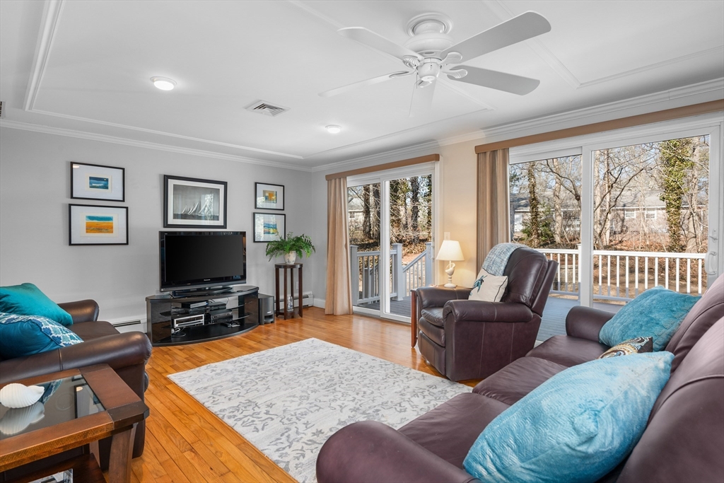 91 Holly Point Road Barnstable, MA 02632 - Photo 3 of 42 a living room with furniture a flat screen tv and a floor to ceiling window