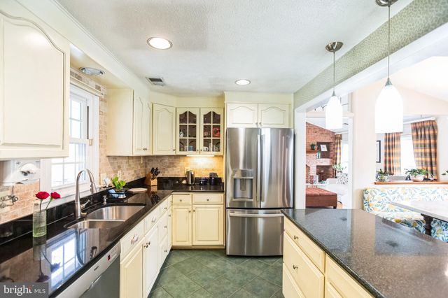 a kitchen with granite countertop a refrigerator a sink a stove and cabinets