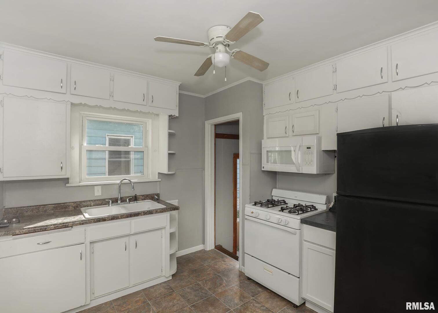 934 20th Avenue Rock Island, IL 61201 - Photo 9 of 26 a kitchen with granite countertop a refrigerator a sink and white cabinets