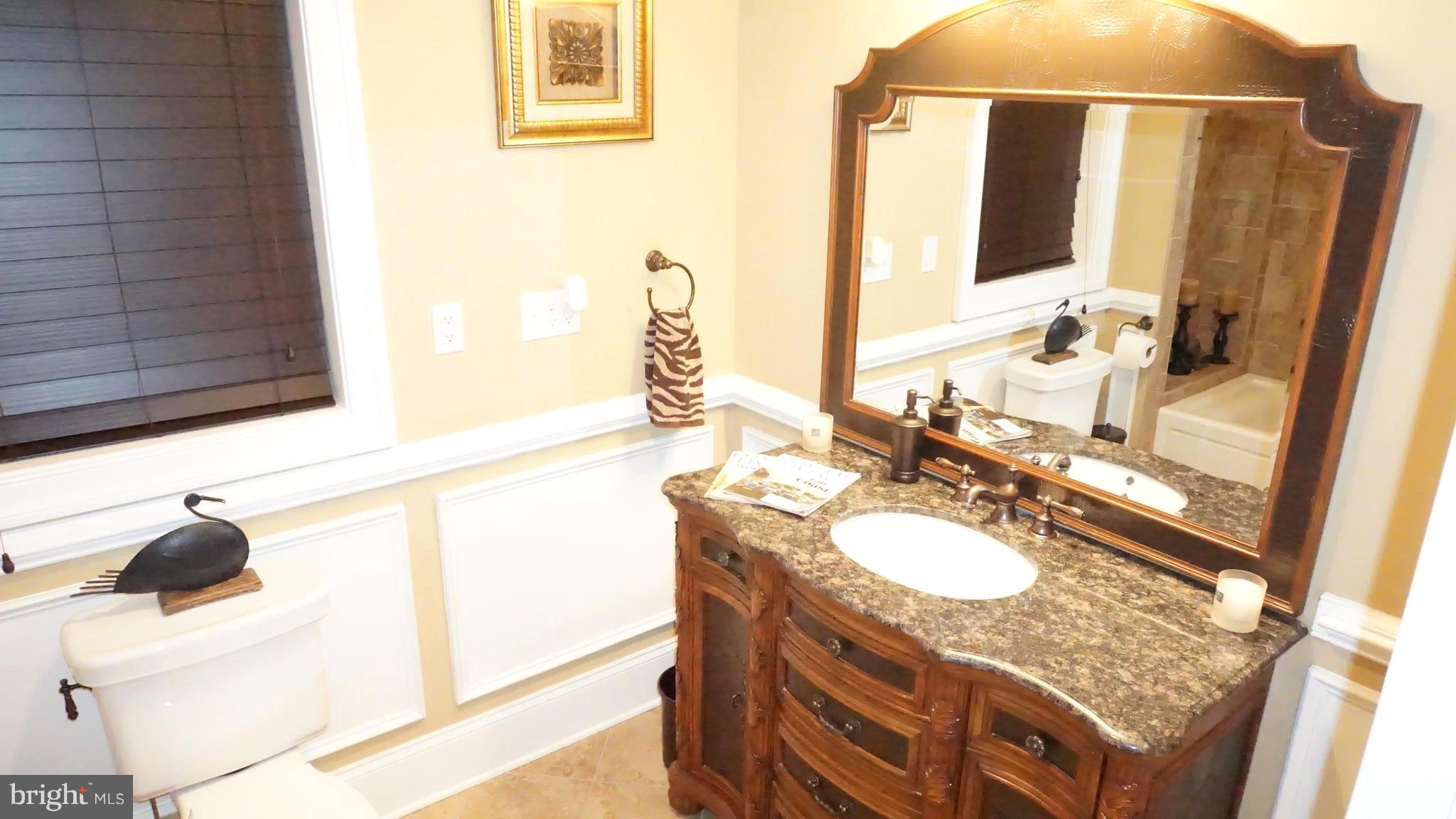 9105 Cuckold Point Road Baltimore, MD 21219 - Photo 31 of 150 a bathroom with a granite countertop sink and a mirror
