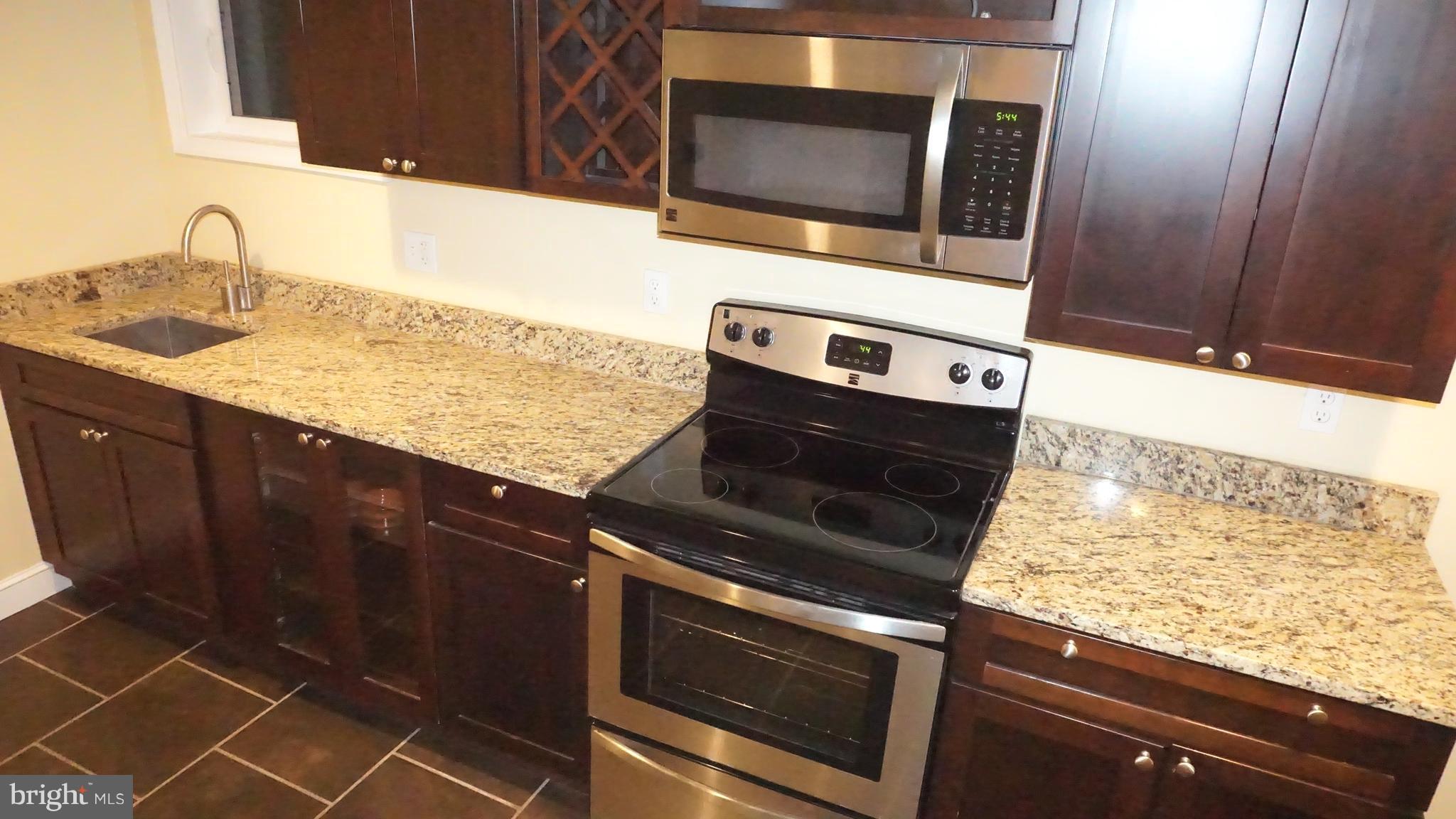 9105 Cuckold Point Road Baltimore, MD 21219 - Photo 77 of 150 a kitchen with granite countertop a sink stove and microwave