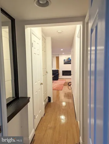 a view of a hallway with wooden floor and a bathroom