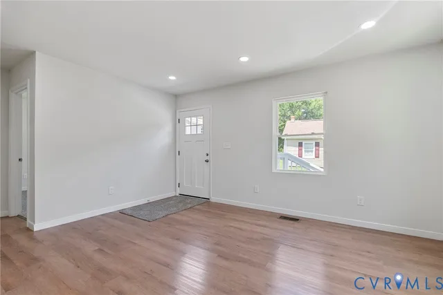 an empty room with wooden floor and windows