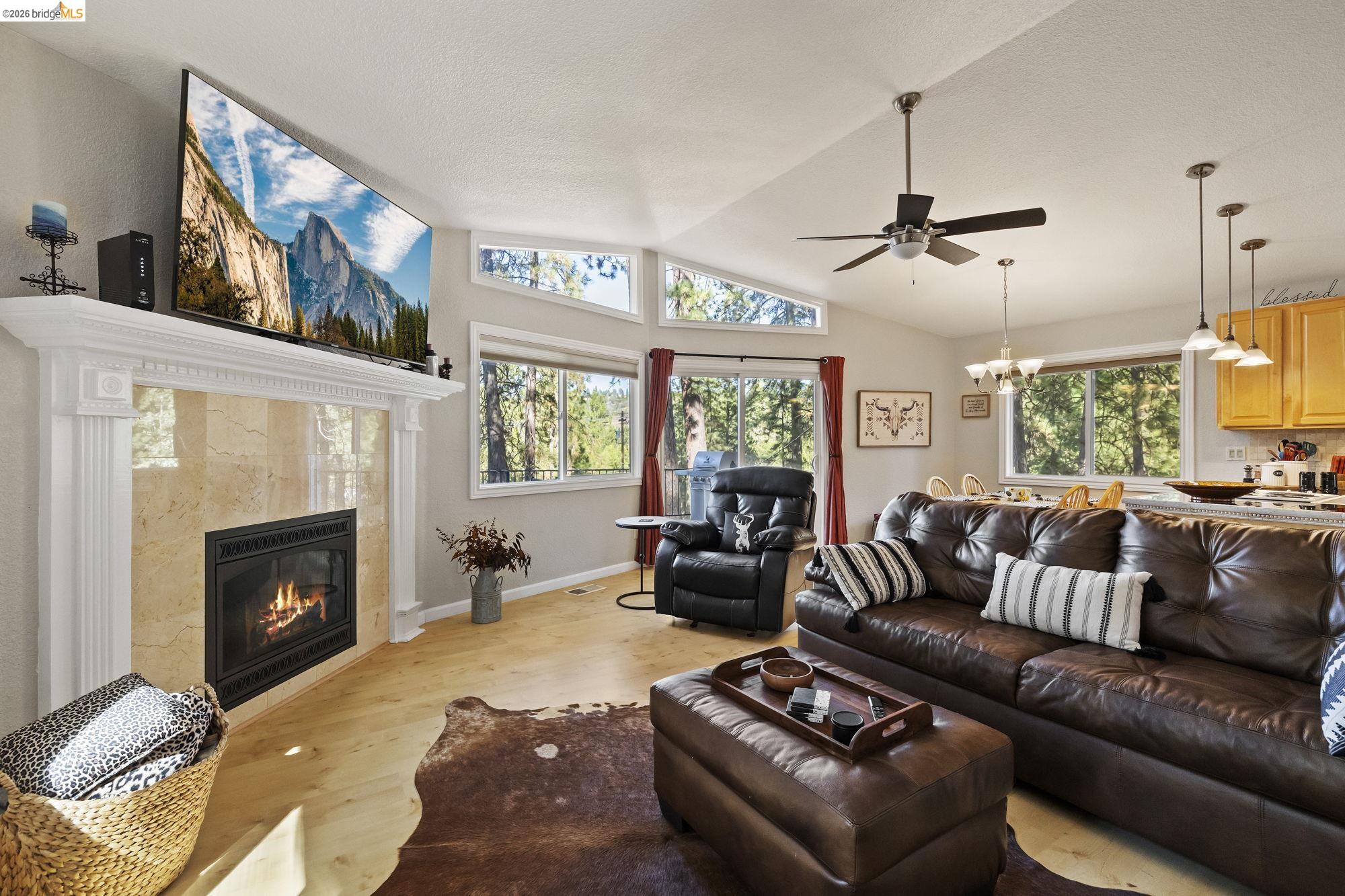 19369 Ferretti Road Groveland, CA 95321 - Photo 8 of 45 Living room with wood finished floors, a tile fireplace, vaulted ceiling, ceiling fan, and a chandelier