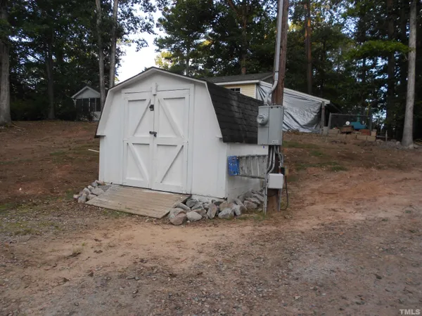 a small barn with a big yard and a large tree