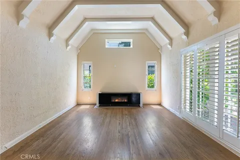 a view of an empty room with wooden floor fireplace and a window