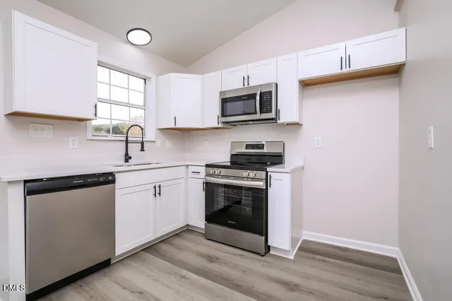 a kitchen with stainless steel appliances granite countertop a sink a stove a microwave and wooden cabinets