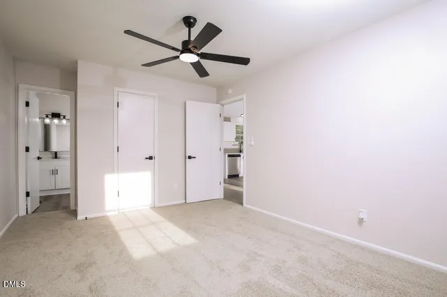 a view of a livingroom with a ceiling fan & kitchen view