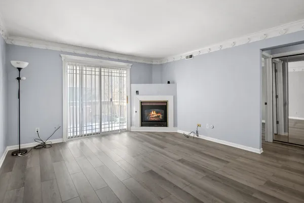 an empty room with wooden floor fireplace and windows