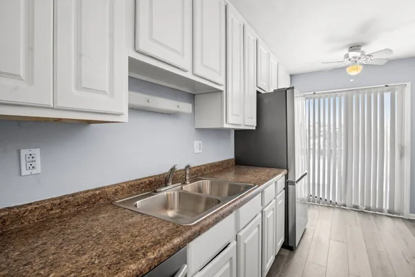a kitchen with stainless steel appliances granite countertop a sink dishwasher and a refrigerator with wooden cabinets