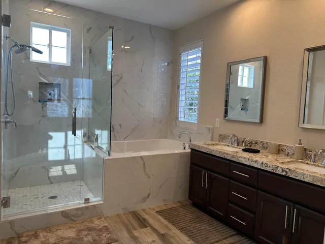 a bathroom with a tub sink mirror and shower