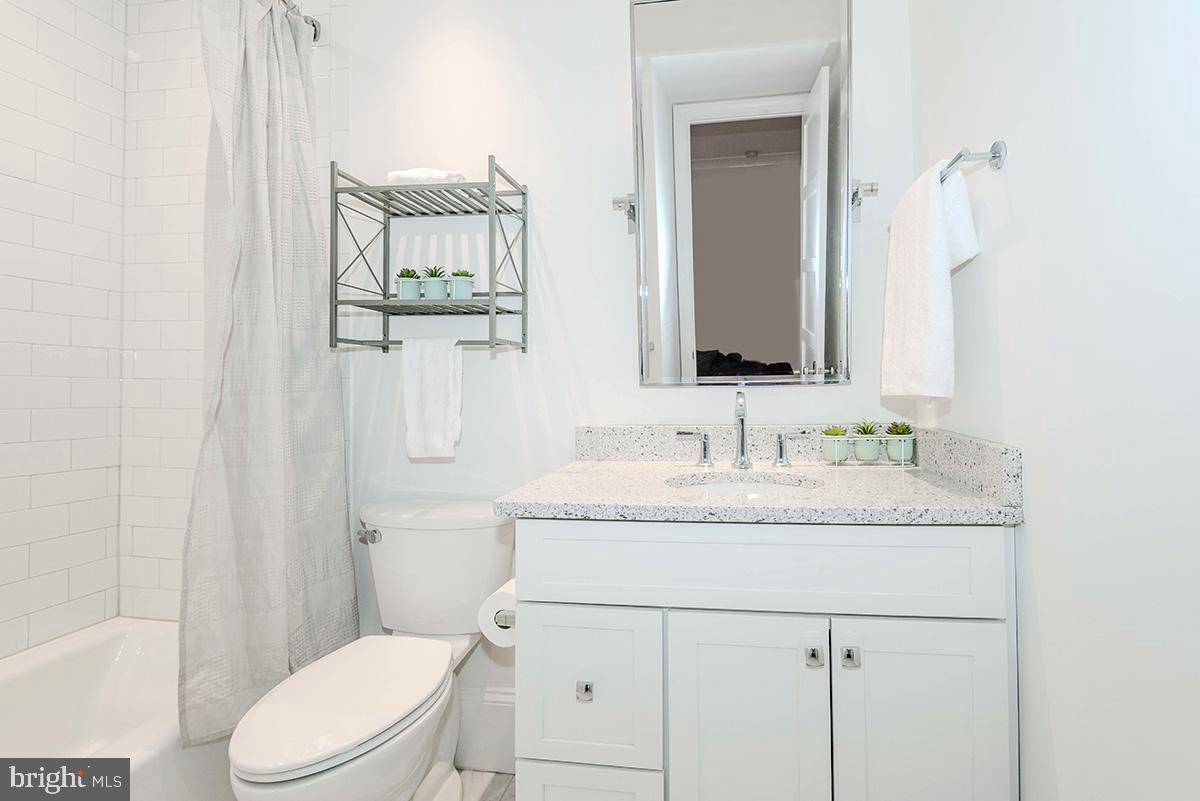 418 7th Street Southeast, Unit 302 Washington, DC 20003 - Photo 14 of 35 a bathroom with a granite countertop toilet sink and mirror