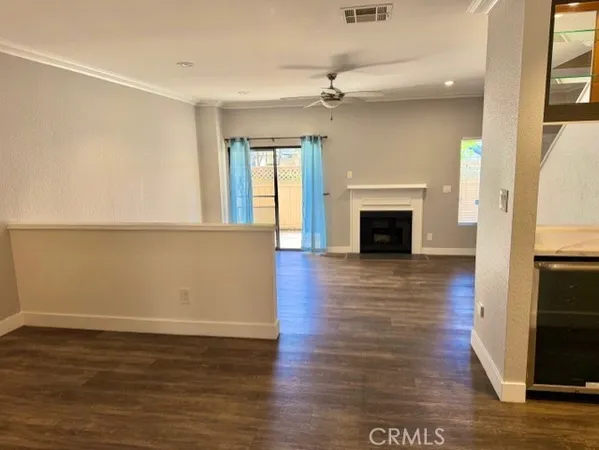 an empty room with wooden floor fireplace and windows