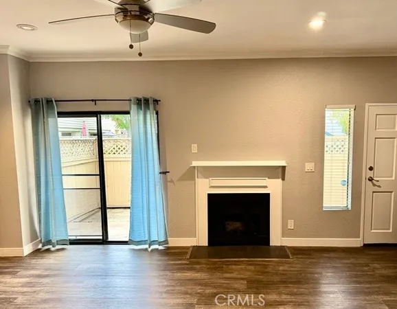 an empty room with wooden floor fireplace and windows