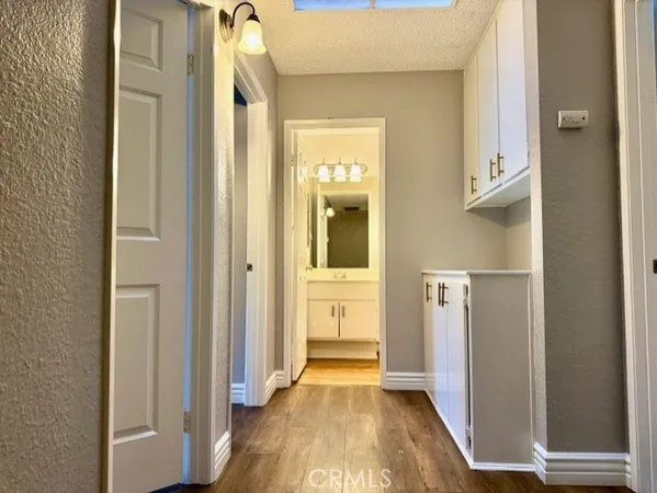 a view of a hallway with wooden floor and a bathroom