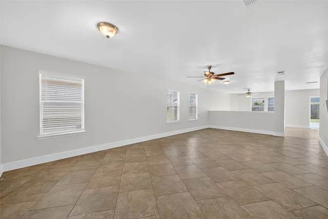 an empty room with chandelier fan and windows