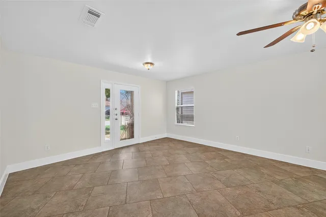 an empty room with windows and chandelier fan