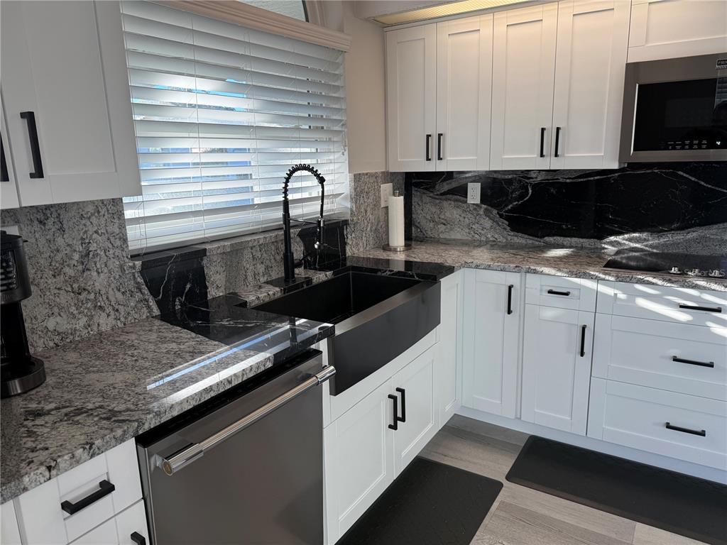 10400 Casa Grande Circle Spring Hill, FL 34608 - Photo 9 of 55 a kitchen with white cabinets and black appliances