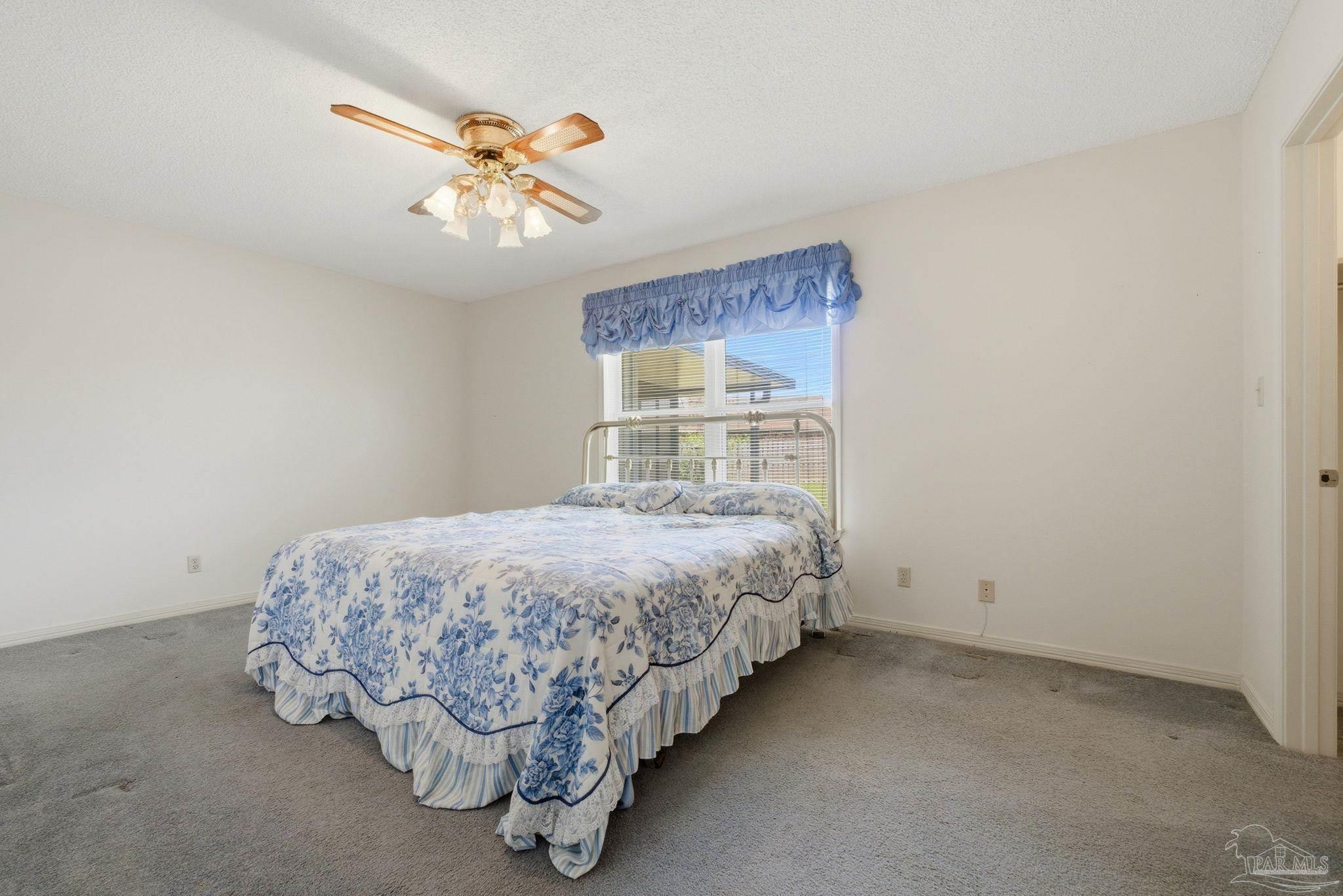 4320 Grant Street Pace, FL 32571 - Photo 22 of 27 a bed sitting in a bedroom next to a window and a chandelier