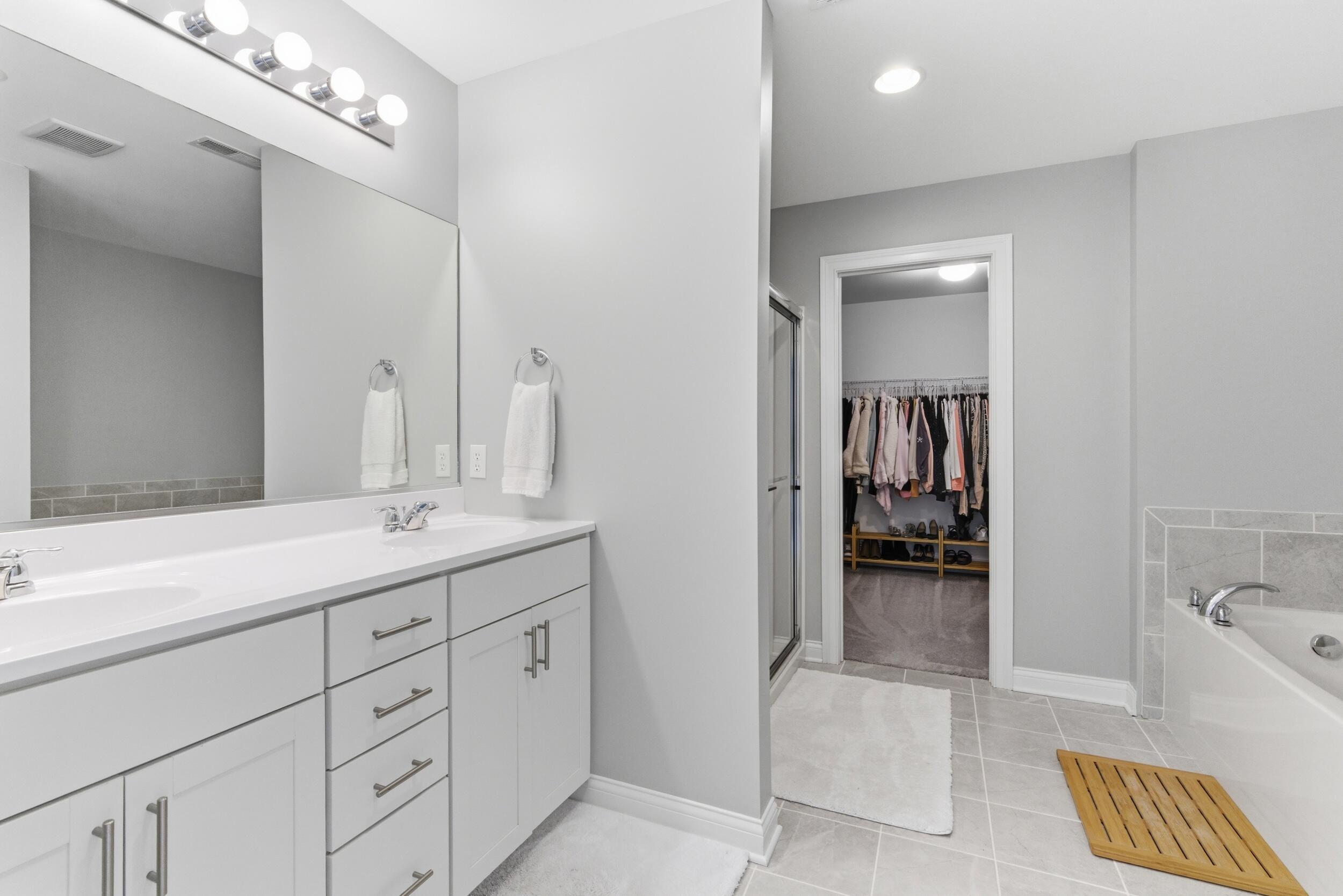 13181 Taft Street Crown Point, IN 46307 - Photo 17 of 42 a en suite bathroom with a double vanity sink a mirror and a bathtub