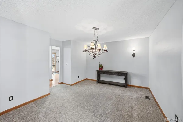 an empty room with chandelier fan and windows