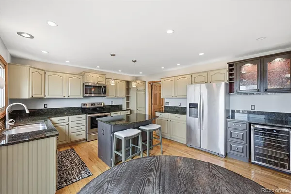 a kitchen with stainless steel appliances granite countertop a stove top oven a sink dishwasher a refrigerator and white cabinets with wooden floor