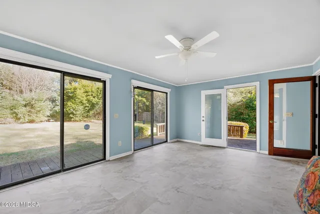 a view of an empty room with window ceiling fan