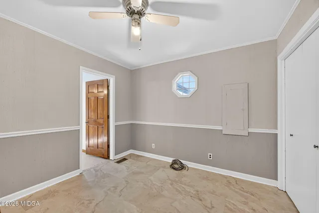 an empty room with windows and fan