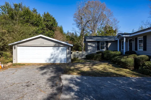 a view of a house with a yard and large tree