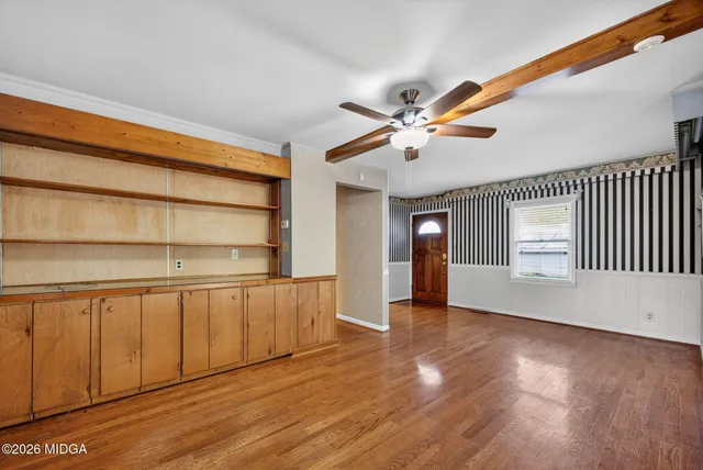 a view of an empty room with a window and wooden floor