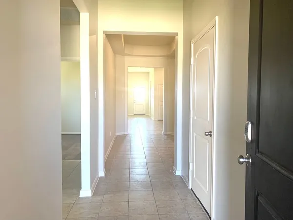 a view of a hallway with wooden floor and a bathroom