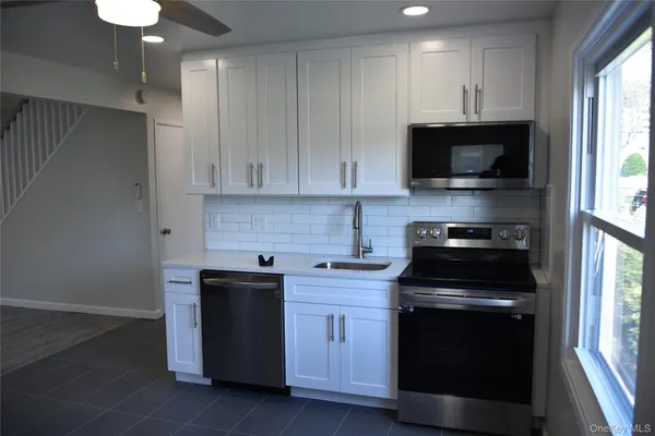 a kitchen with stainless steel appliances granite countertop a stove a sink and a microwave